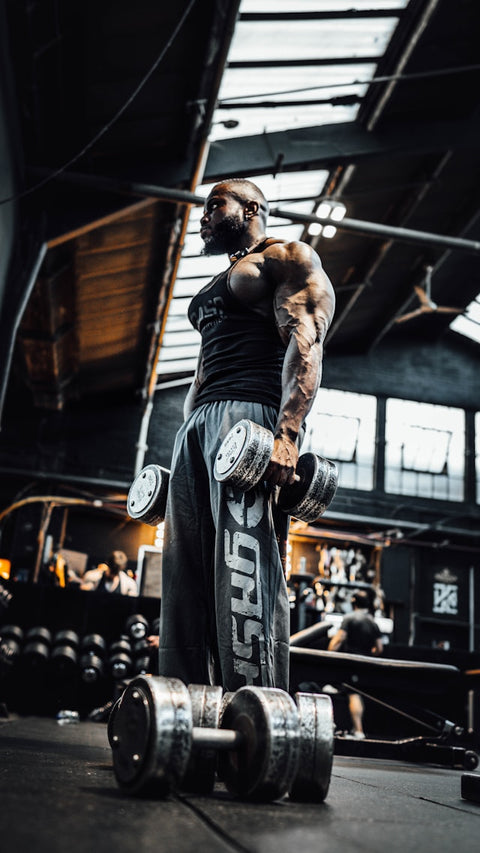 Bodybuilder standing in the gym holding dumbells